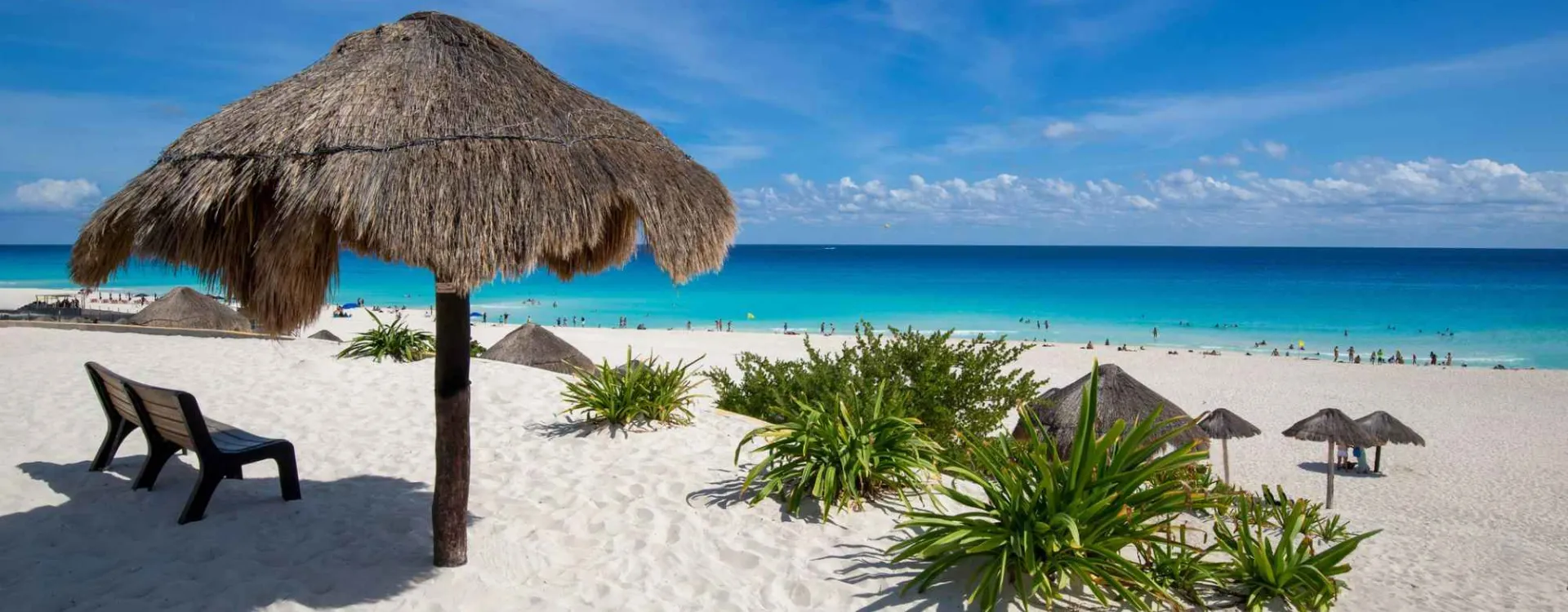 Plage de sable blanc avec palapas et eaux turquoise à Cancún au Mexique