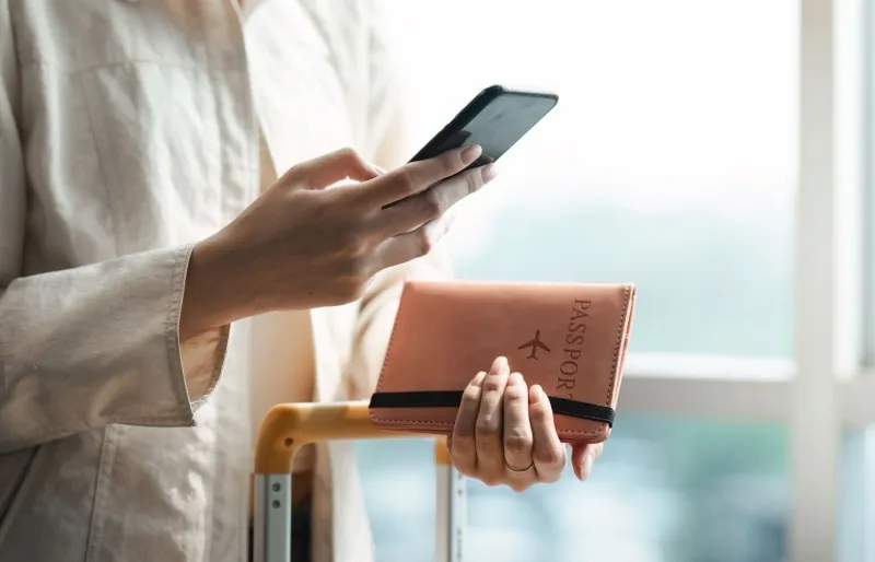 Une femme à l'aéroport avec son passeport et son téléphone.