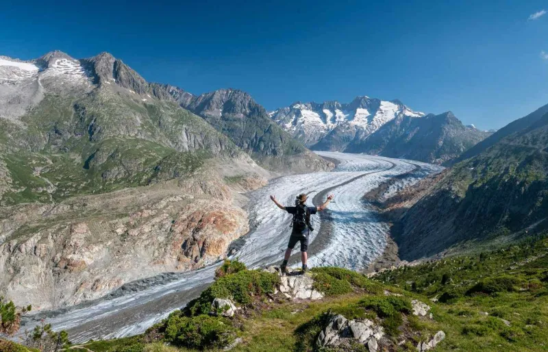 Randonneur vu de dos face au glacier d’Aletsch en Suisse
