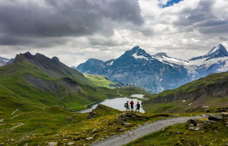 Randonneurs face au lac Bachalpsee avec les sommets du Schreckhorn et du Finsteraarhorn dans l’Oberland bernois