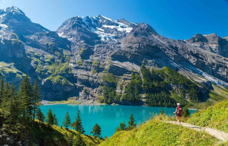 Randonneuse face au lac d’Oeschinen lors d’une étape de la Via Alpina