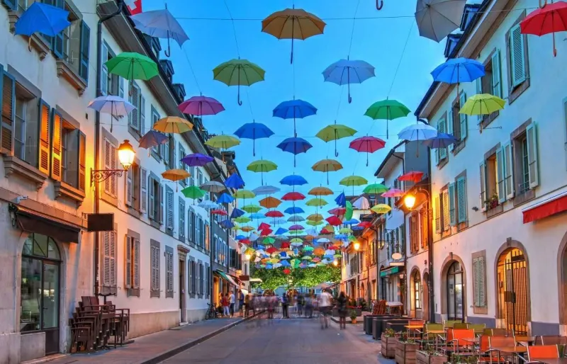 Parapluies multicolores suspendus dans une rue du quartier de Carouge à Genève
