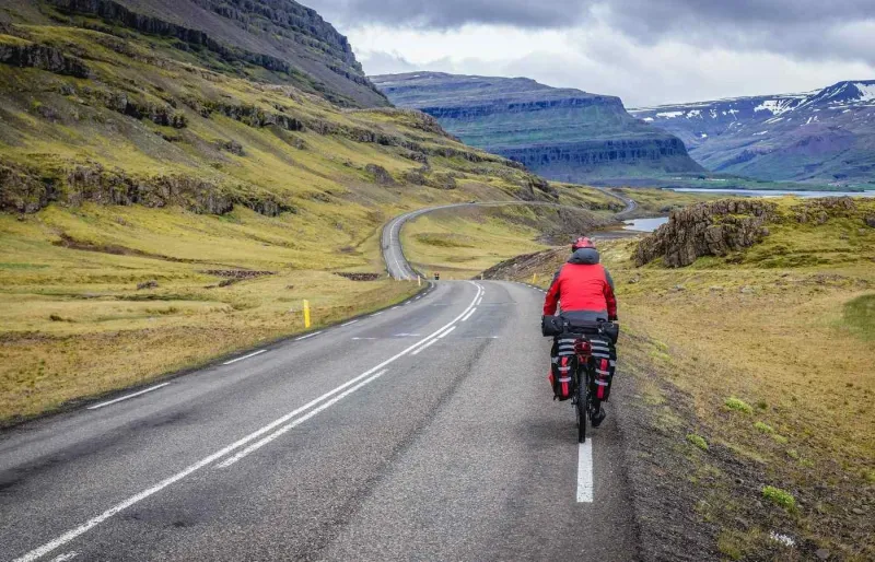 Cycliste équipé d’une veste imperméable et de sacoches sur la route 1 en Islande