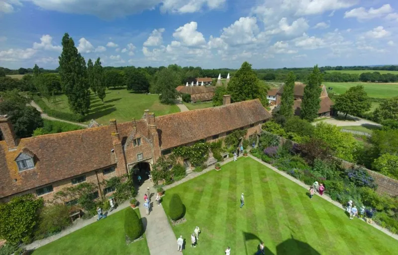 Vue aérienne de visiteurs se promenant dans les jardins de Sissinghurst Castle, avec allées paysagées et espaces clos