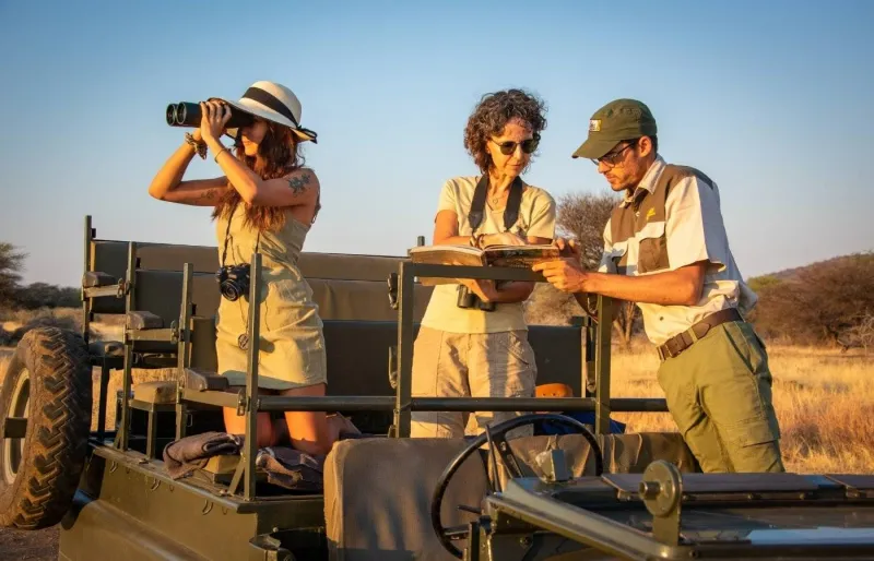 Guide de safari échangeant avec deux voyageuses lors d’une observation