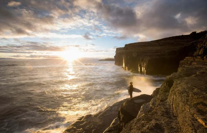 Surfeur observant l’océan depuis les falaises de Shipstern Bluff, Tasmanie