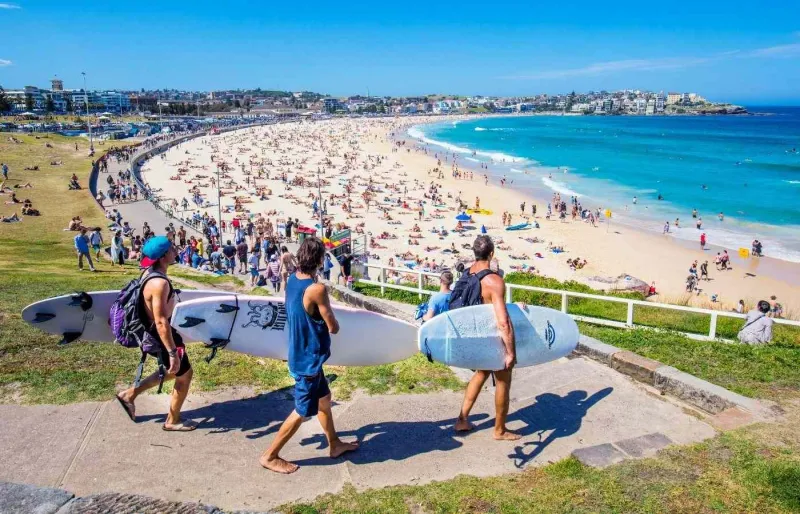 Trois surfeurs marchant vers Bondi Beach avec leurs planches à Sydney, Australie