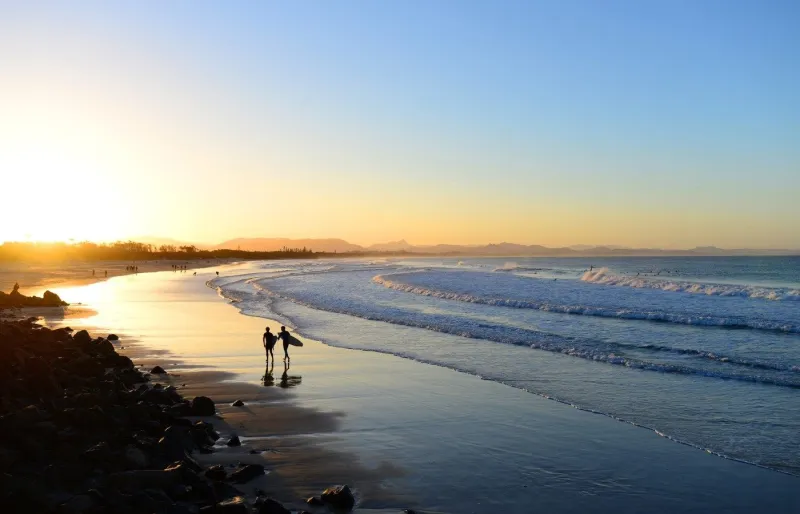 Deux surfeurs sur la plage de Byron Bay au coucher du soleil, Australie