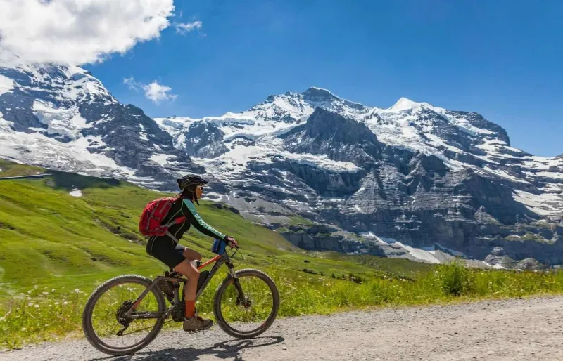 Femme senior souriante roulant à vélo électrique en montagne dans les Alpes suisses