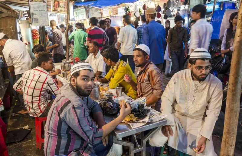 Personnes musulmanes partageant un repas de rupture du jeûne dans un stand de street food sur Mohammad Ali Road à Mumbai pendant le mois de Ramadan.