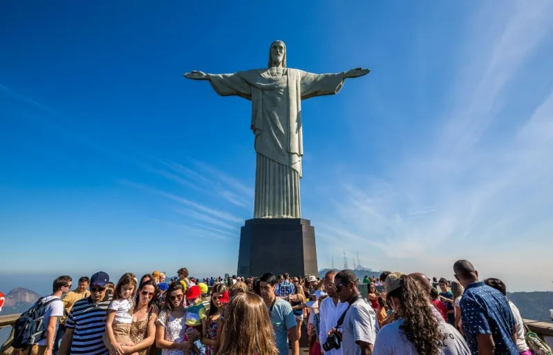 Touristes devant la statue du Christ Rédempteur au sommet du mont Corcovado à Rio de Janeiro, au Brésil
