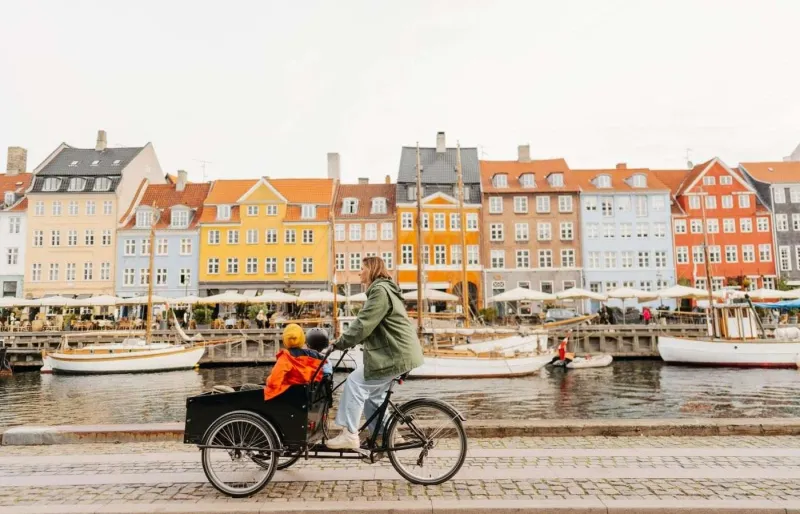 Famille à vélo cargo le long du canal de Nyhavn à Copenhague, symbole du mode de vie danois