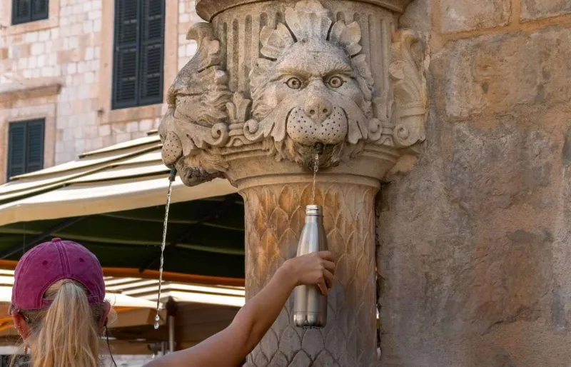 Touriste remplissant sa gourde à une fontaine de la vieille ville de Dubrovnik