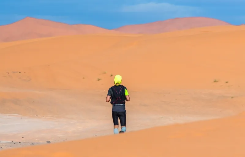 Coureur participant au Marathon des Sables traversant les dunes du désert du Sahara au Maroc