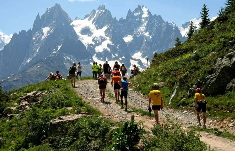 Coureurs du Marathon du Mont-Blanc sur un sentier de trail face aux aiguilles de Chamonix dans les Alpes