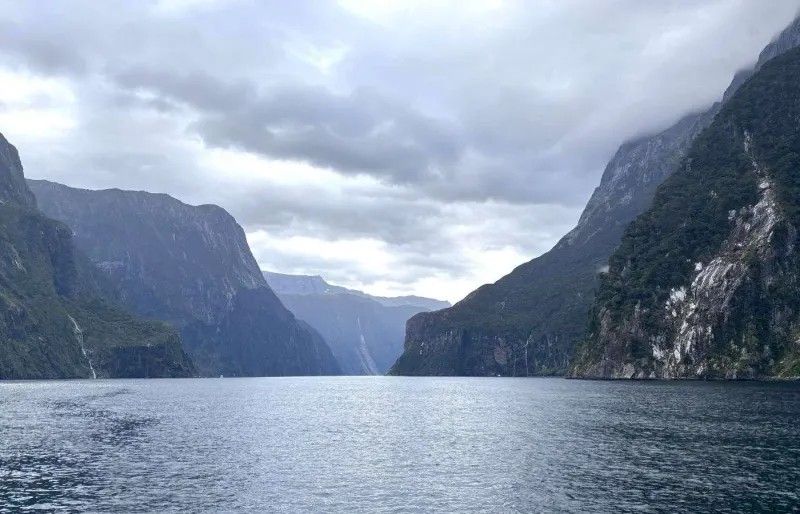 Milford Sound en Nouvelle-Zélande, fjord entouré de montagnes abruptes et de cascades sous un ciel nuageux
