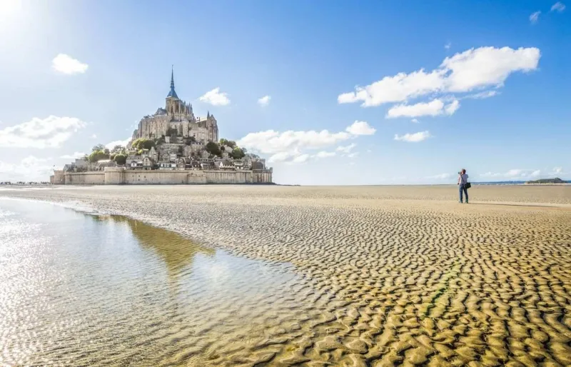 Mont-Saint-Michel vue panoramique avec touriste prenant une photo baie Normandie été ciel bleu