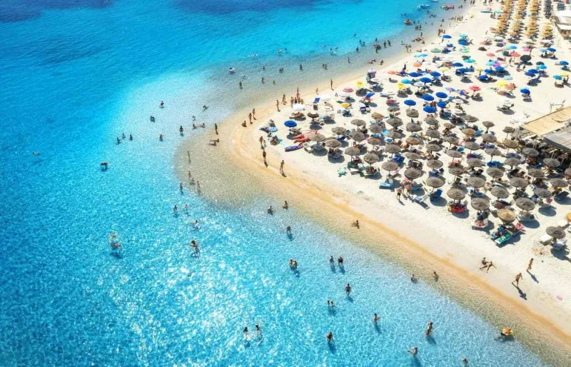 Vue aérienne de la plage de Tuerredda en Sardaigne avec parasols colorés et eau turquoise en été