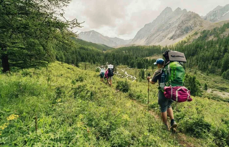 Famille avec enfants en randonnée en montagne avec sacs à dos lors d’un voyage en famille