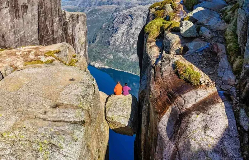 eux randonneurs assis sur le rocher Kjeragbolten au-dessus du Lysefjord en Norvège
