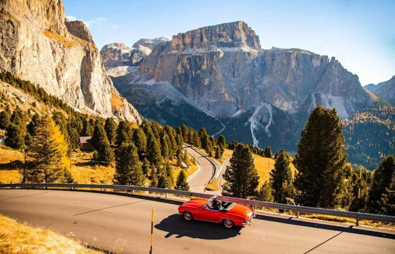 Voiture décapotable rouge sur une route panoramique dans les Dolomites en Italie