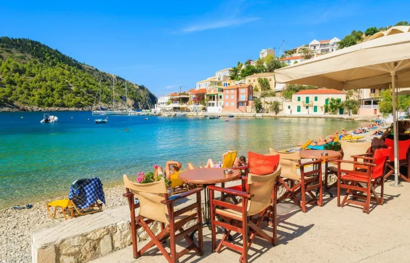 Tables d’une taverne en bord de mer sur une plage de Zakynthos avec vue sur l’eau turquoise