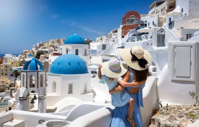 Mère et sa fille admirant les maisons blanches du village d’Oia à Santorin pendant un voyage en famille