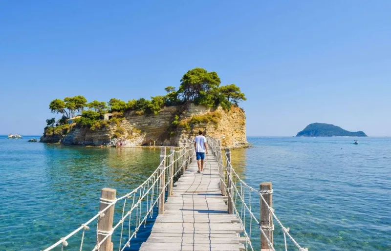 Un pont en bois mène à une petite île au large de Zakynthos sous un ciel dégagé en été en Grèce