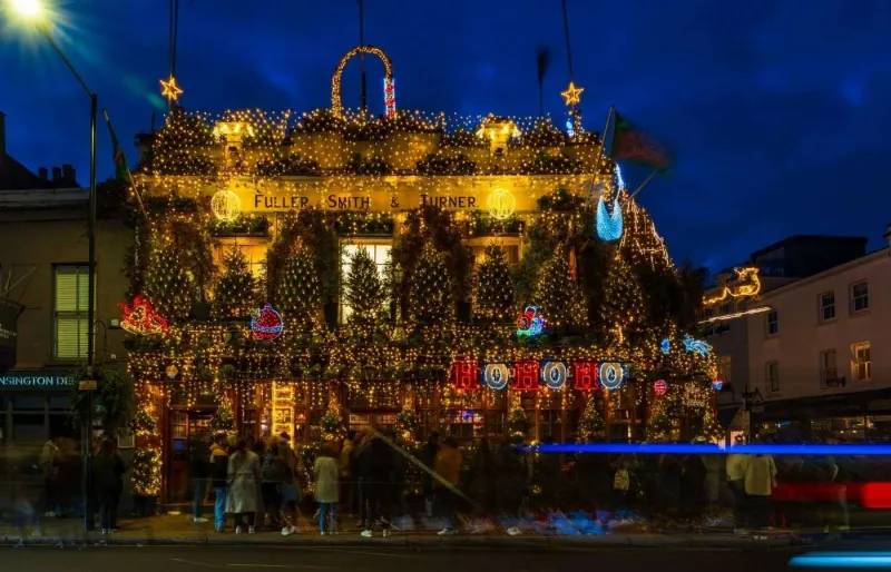 Pub Churchill Arms à Londres décoré pour Noël avec guirlandes lumineuses et façade festive