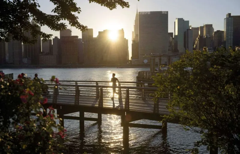 Silhouette d’un homme courant le long de l’East River avec vue sur la skyline de Manhatta