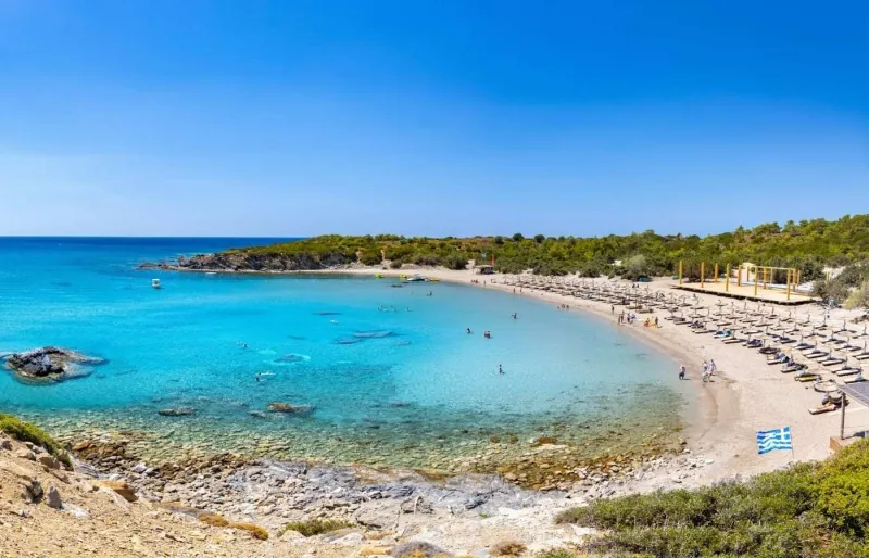 Plage de Glystra à Rhodes avec parasols et eaux turquoise peu profondes