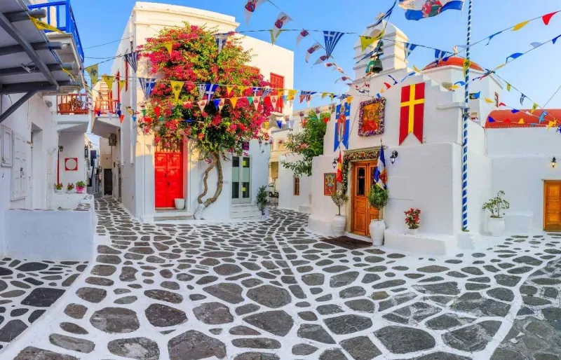 Ruelle typique de Hora à Mykonos avec maisons blanches, pavés et bougainvilliers colorés
