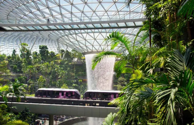 Cascade intérieure Jewel Changi Airport à Singapour avec train Skytrain et jardin tropical
