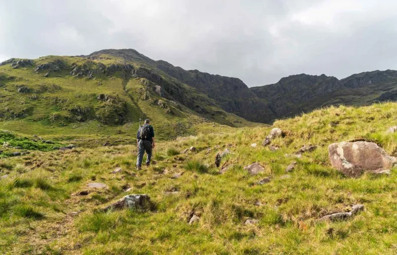 Randonneur sur le sentier du Mweelrea avec le sommet de Ben Lugmore