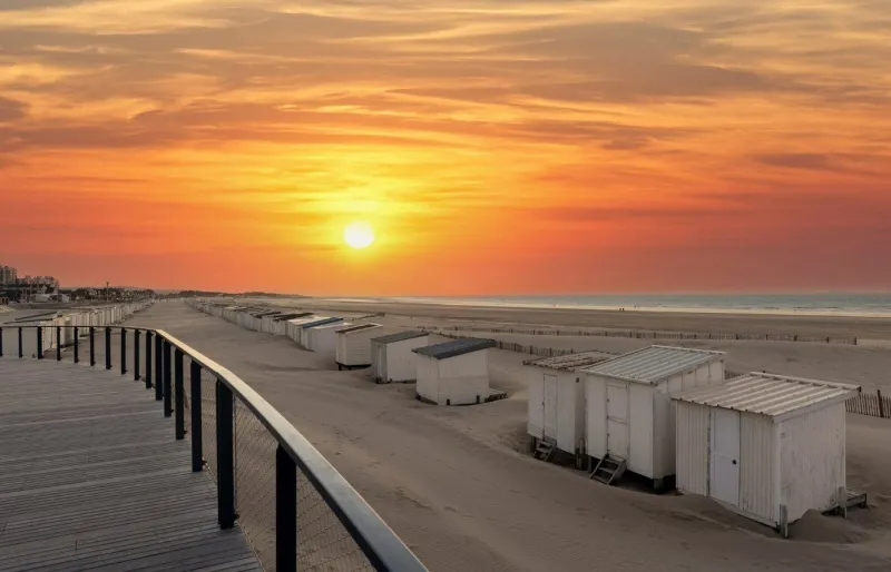 Plage de Calais au coucher de soleil avec cabines de plage et promenade sur la Côte d’Opale