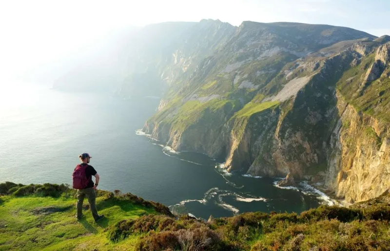 Randonneur face aux falaises de Slieve League dans le Donegal, sur la côte sauvage de l’Irlande
