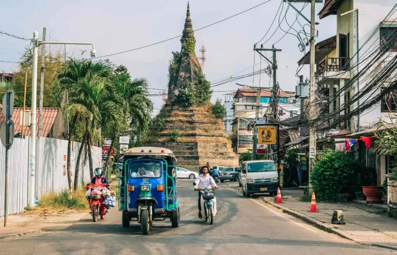 Tuk-tuk circulant dans une rue de Vientiane, moyen de transport courant pour se déplacer en ville