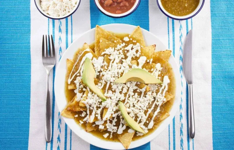 Chilaquiles traditionnels mexicains avec sauce verte, avocat et fromage frais