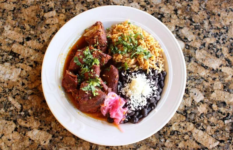 Cochinita pibil traditionnelle du Yucatán avec porc mariné, haricots noirs et oignons rouges