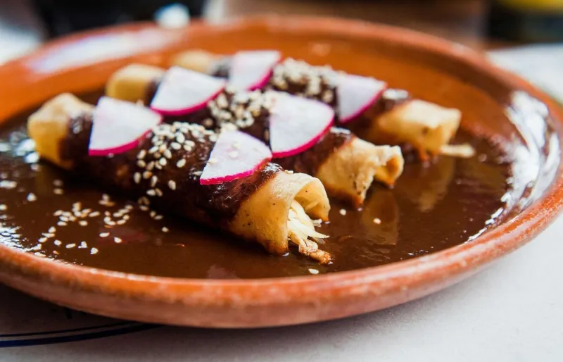 Enchiladas au poulet nappées de mole poblano traditionnel, spécialité emblématique de la cuisine mexicaine