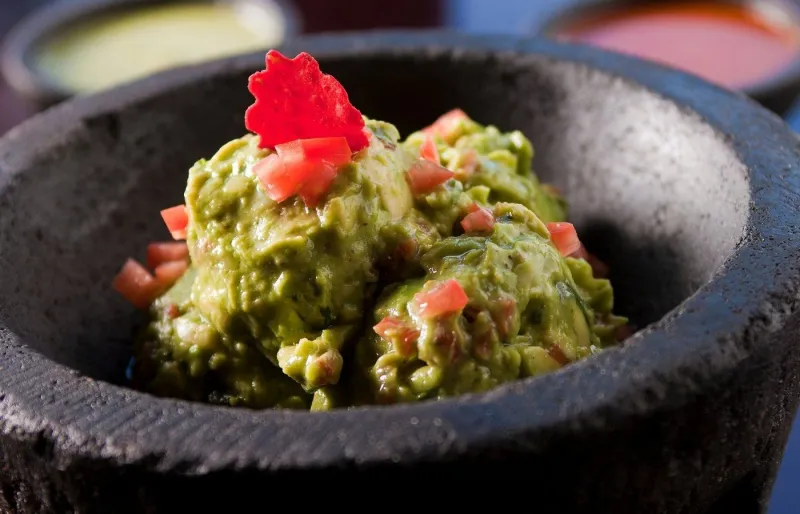 Guacamole traditionnel mexicain préparé avec avocat frais, tomates et coriandre