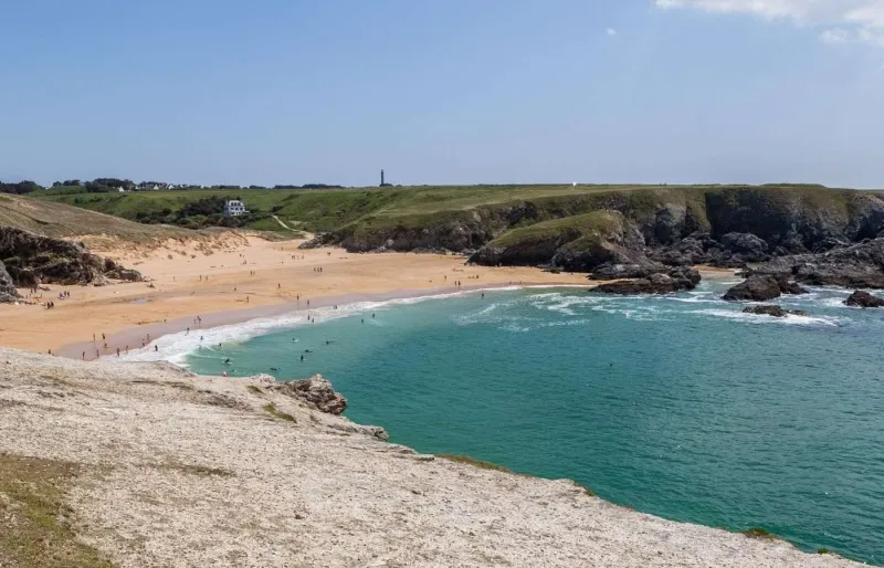 Plage de Donnant à Belle-Île-en-Mer avec sable blond et falaises sur la côte sauvage du Morbihan  Légende SEO