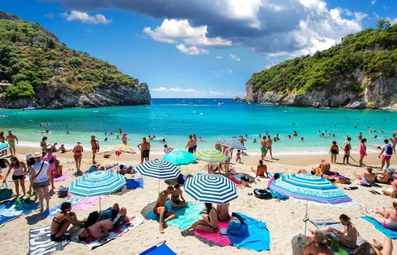Vue de la plage de Paleokastritsa à Corfou en Grèce avec eau turquoise, sable clair et falaises verdoyantes