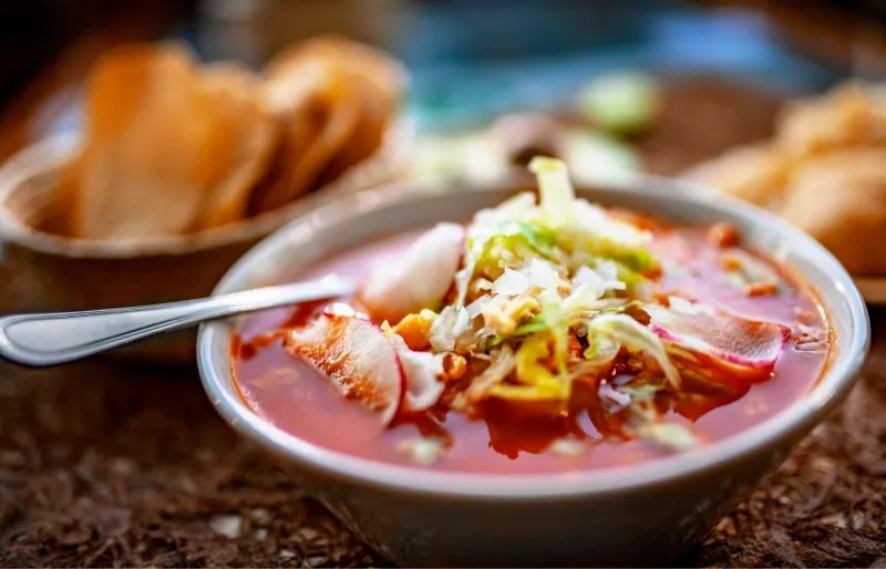 Pozole traditionnel mexicain servi avec maïs, avocat, citron vert et chicharrón