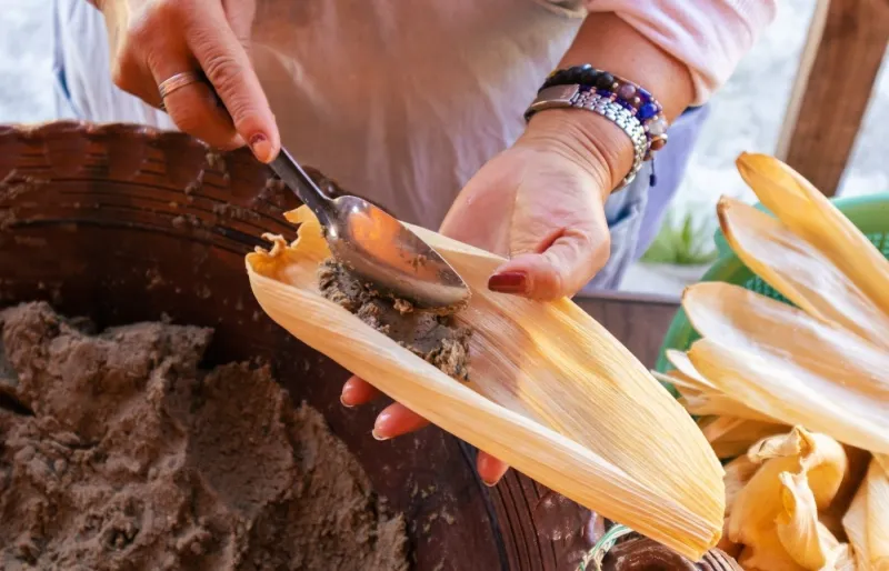 Préparation artisanale de tamales mexicains dans une feuille de maïs, spécialité traditionnelle du Mexique