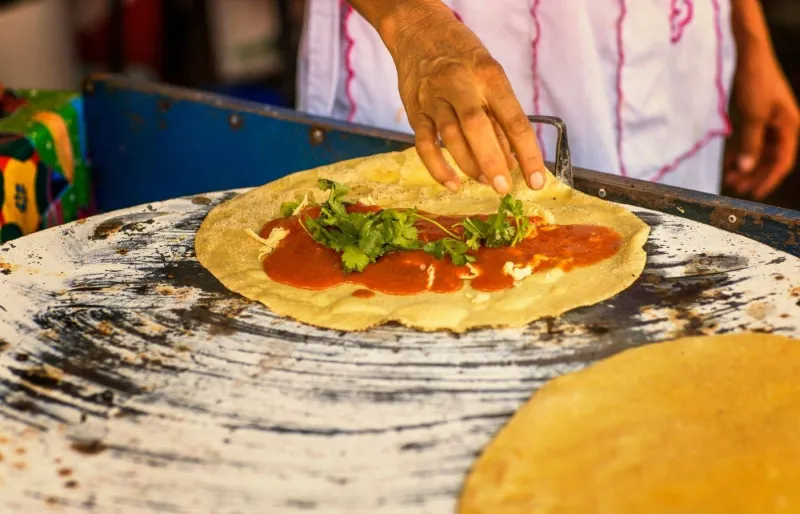 Préparation d’une quesadilla traditionnelle mexicaine avec sauce mole amarillo dans l’État de Oaxaca