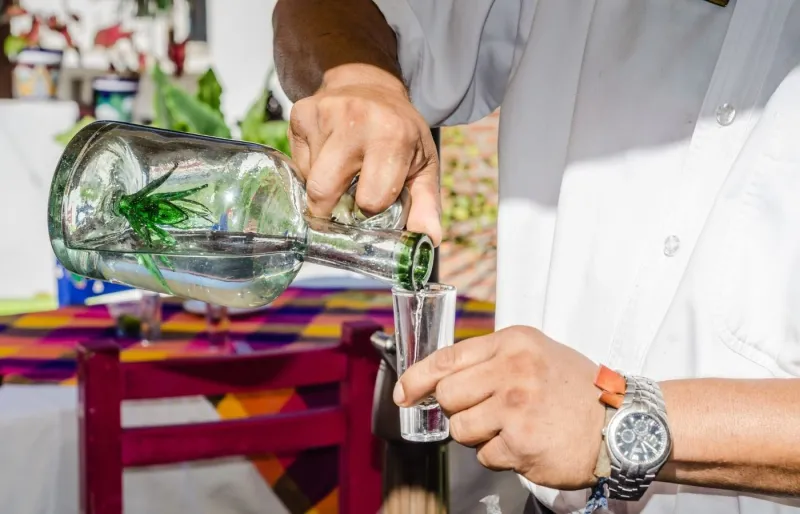 Serveur versant un shot de tequila mexicaine à base d’agave dans un bar au Mexique
