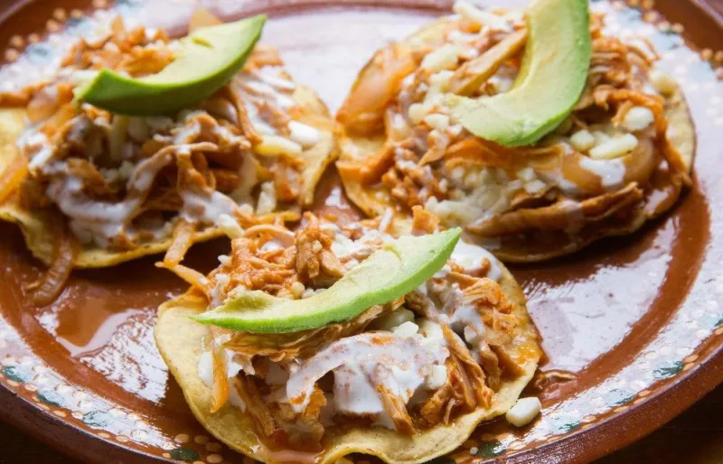 Tostadas mexicaines garnies de tinga de poulet, salade et fromage frais