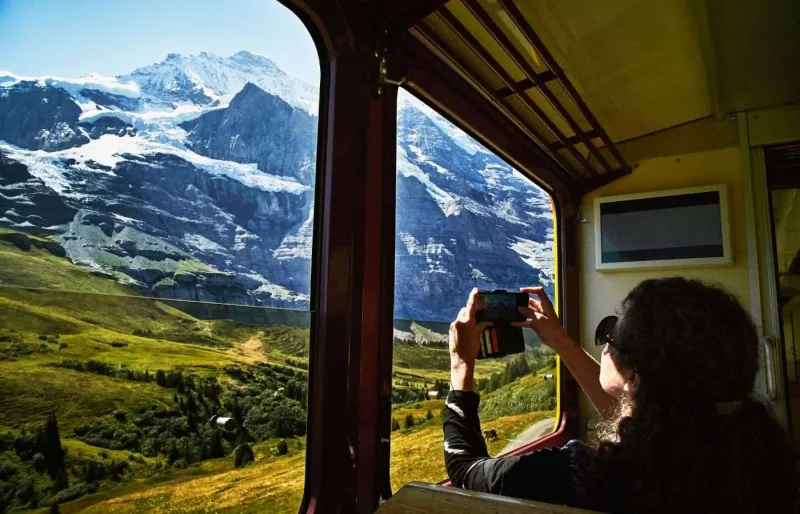 Voyageuse photographiant les sommets de la Jungfrau depuis le train entre Interlaken et Kleine Scheidegg en Suisse