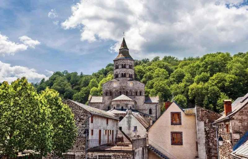 Basilique Notre-Dame d'Orcival dominant les toits du village, au cœur du Puy-de-Dôme en Auvergne.